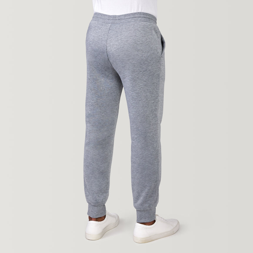 A person wearing Free Country Men’s Sherpa Lined Jogger and white sneakers stands on a light background—ideal for fans of comfortable athleisure wear.