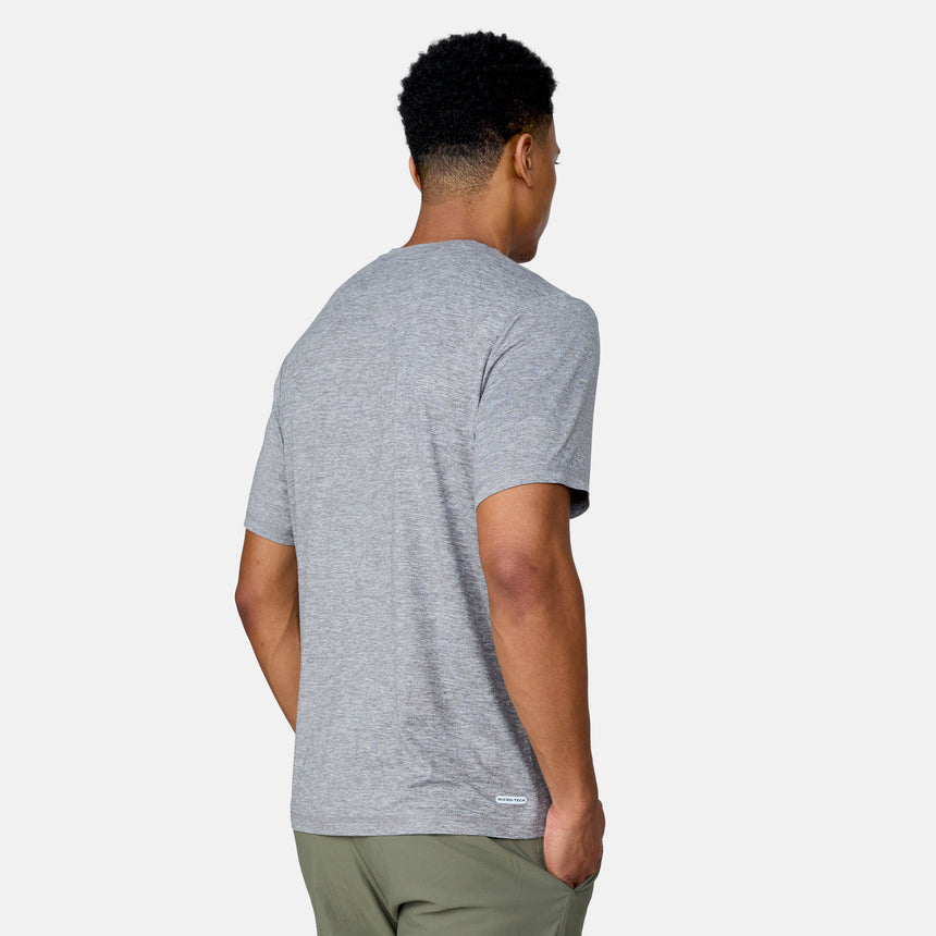 A man stands facing away, wearing the Clearance Men's Super Soft Short Sleeve Crew Tee in heather gray from a 2-pack, paired with olive green pants, his left hand in his pocket against a plain light background.