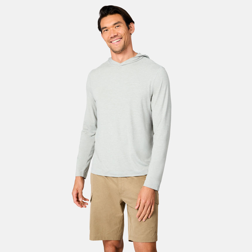 A man wears the Free Country Men's Microtech® Hooded Graphic Sunshirt in light gray and tan cargo shorts, smiling against a plain white background.