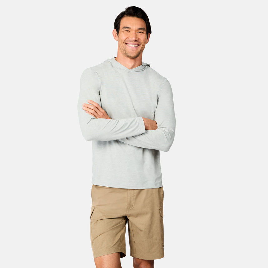 A man stands smiling with arms crossed, wearing the Free Country Men's Microtech® Hooded Graphic Sunshirt and tan cargo shorts, against a plain light gray background.