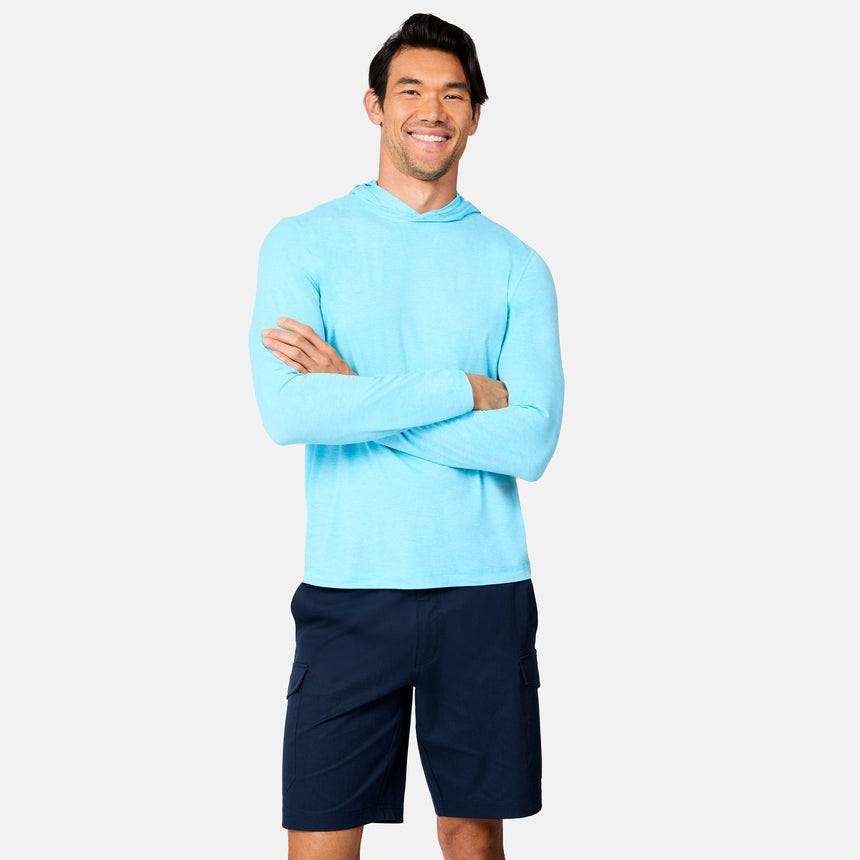 A man stands smiling with arms crossed, wearing a Free Country Men's Microtech® Hooded Graphic Sunshirt and dark blue cargo shorts against a plain white background.