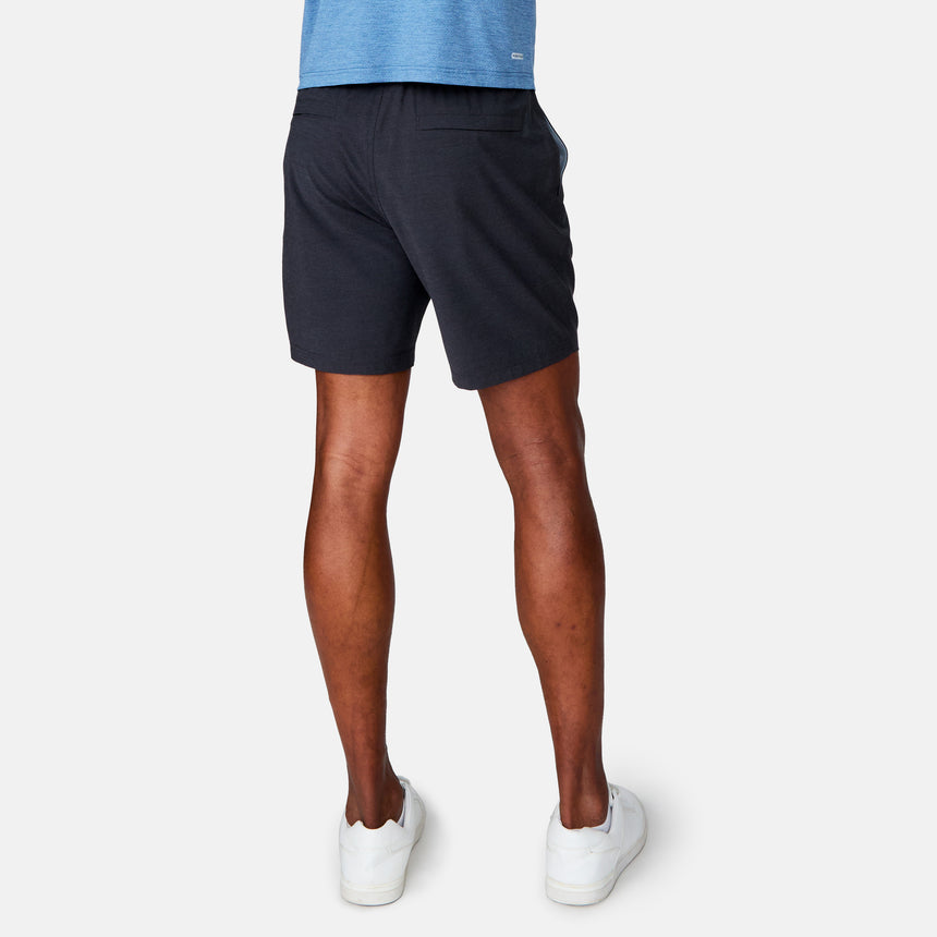 A person stands facing away, displaying the back view of the outfit—a blue shirt and Clearance Men's Trek Short in black—against a plain light background, also wearing white sneakers.