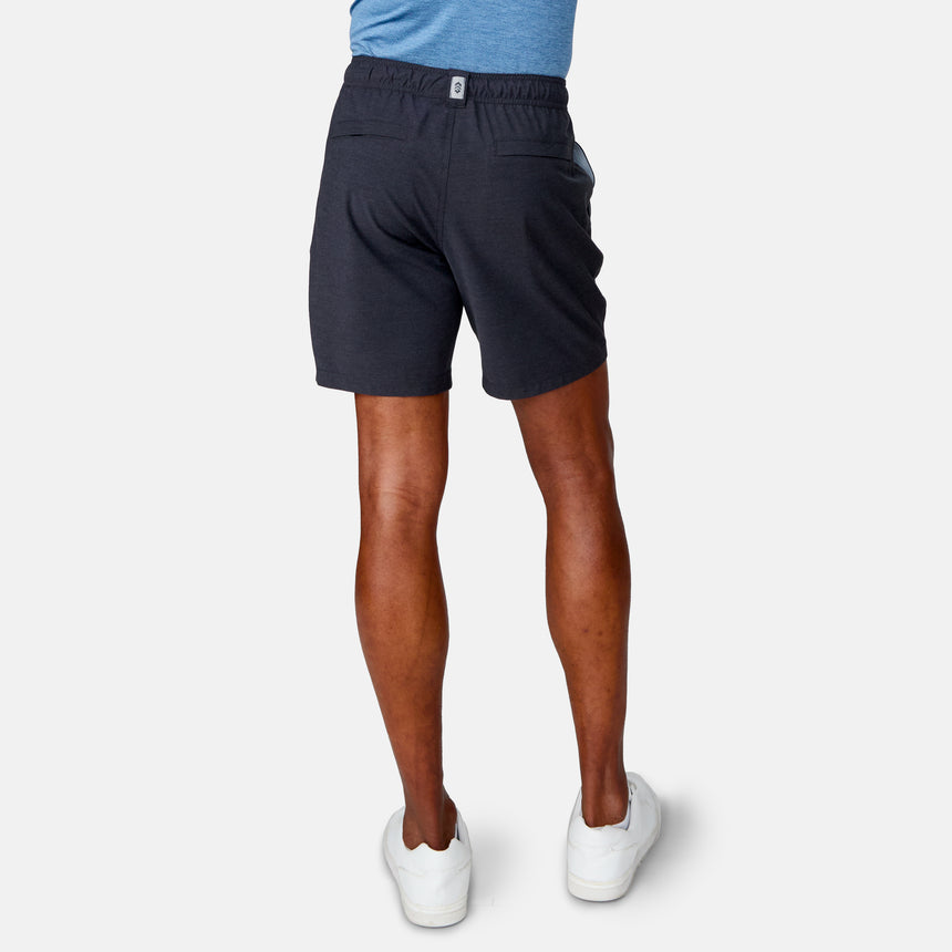 A person is shown from the back wearing Clearance Men's Trek Short in dark gray with a blue shirt and white sneakers, standing against a plain light background.