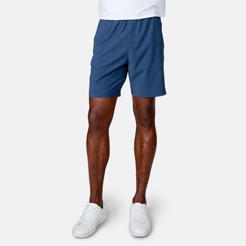 A person wears Clearance Men's Trek Shorts in blue, paired with a white shirt and white sneakers, standing against a plain white background. Only the lower half of the body is shown.