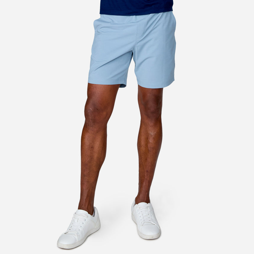 A person models the Clearance Men's Trek Short in light blue, paired with white sneakers, standing against a plain white background. The image is cropped at the waist to display only the lower body and legs.