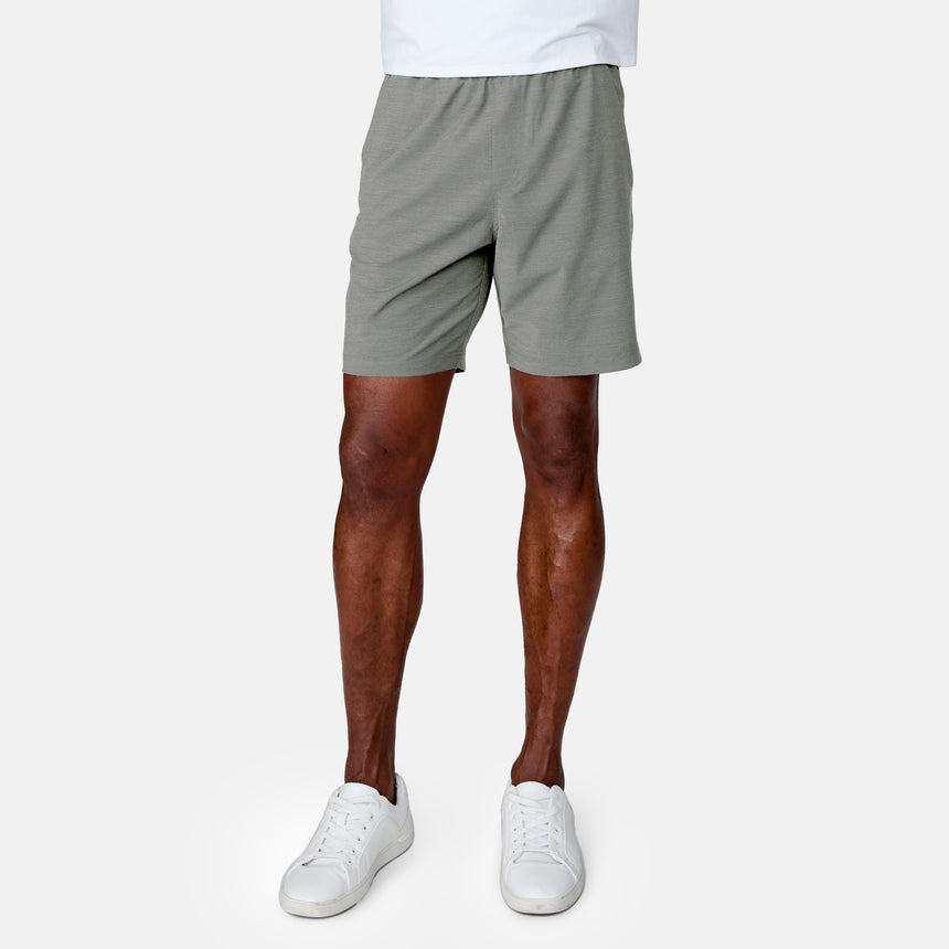 A person wears the Clearance Men's Trek Short in light gray, paired with a white shirt and sneakers, standing against a plain white background. Only the lower torso and legs are shown.