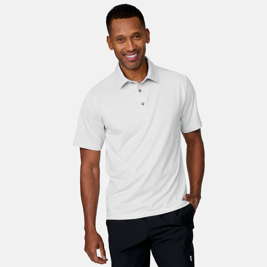 A man smiles while wearing the Clearance Men's Tech Pique Polo Shirt in light gray and black pants, standing against a plain white background.