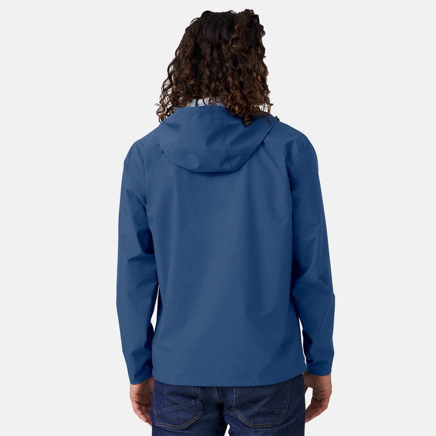A person with long curly hair, seen from the back against a plain light background, wears blue jeans and the Clearance Men's Hydro Lite X2O Highline Waterproof Jacket in blue, made with lightweight stretch fabric.