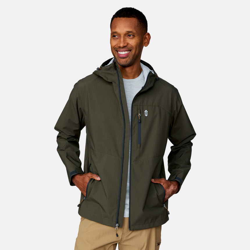 A man smiles with his hands in his pockets, wearing the Clearance Men's Hydro Lite X2O Highline Waterproof Jacket in olive green over a light gray shirt and tan pants, set against a plain light background.