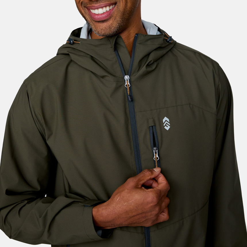 A man smiles as he unzips the chest pocket of the olive green Clearance Men's Hydro Lite X2O Highline Waterproof Jacket, featuring a small white chest logo, stretch fabric for comfort, and a front zipper. The background is plain and light-colored.
