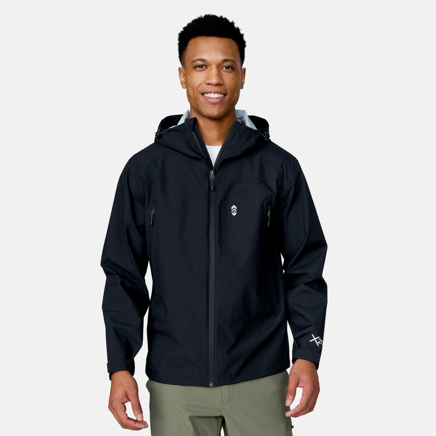 A man faces forward, smiling, wearing the Clearance Men's Hydro Lite X2O Squall Rain Jacket in black with subtle white logos and light green pants against a plain light gray background.