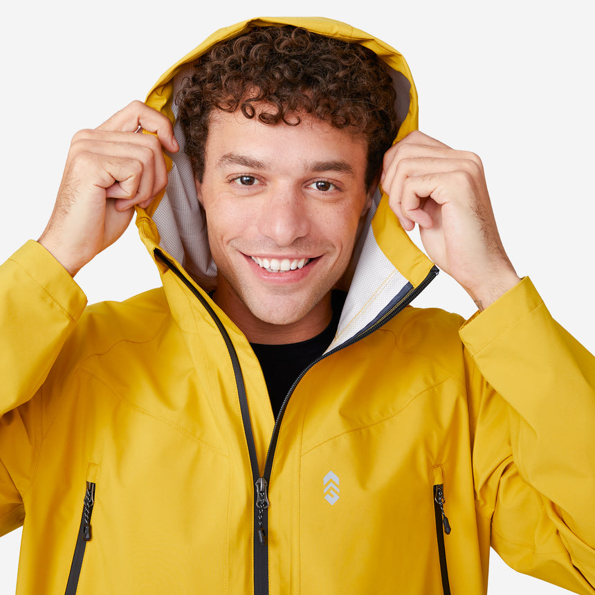 A person smiles while putting on the hood of the Clearance Men's Hydro Lite X2O Squall Rain Jacket in bright yellow, featuring zippered pockets and a small white chest logo, set against a plain white background.
