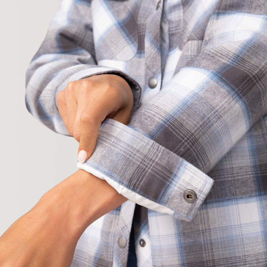 Woman wearing Free Country Women's Koshi Adirondack Flannel Shirt Jacket in grey and white plaid with a full front button opening, soft lining, chest pockets, light grey background. Best women’s jacket for winter weather.