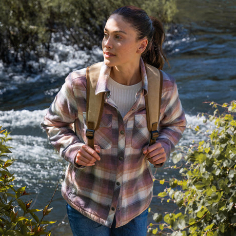 Woman wearing Free Country Women's Koshi Adirondack Flannel Shirt Jacket in pink and blue and white plaid with a full front button opening, soft lining, chest pockets, light grey background. Best women’s jacket for winter weather.