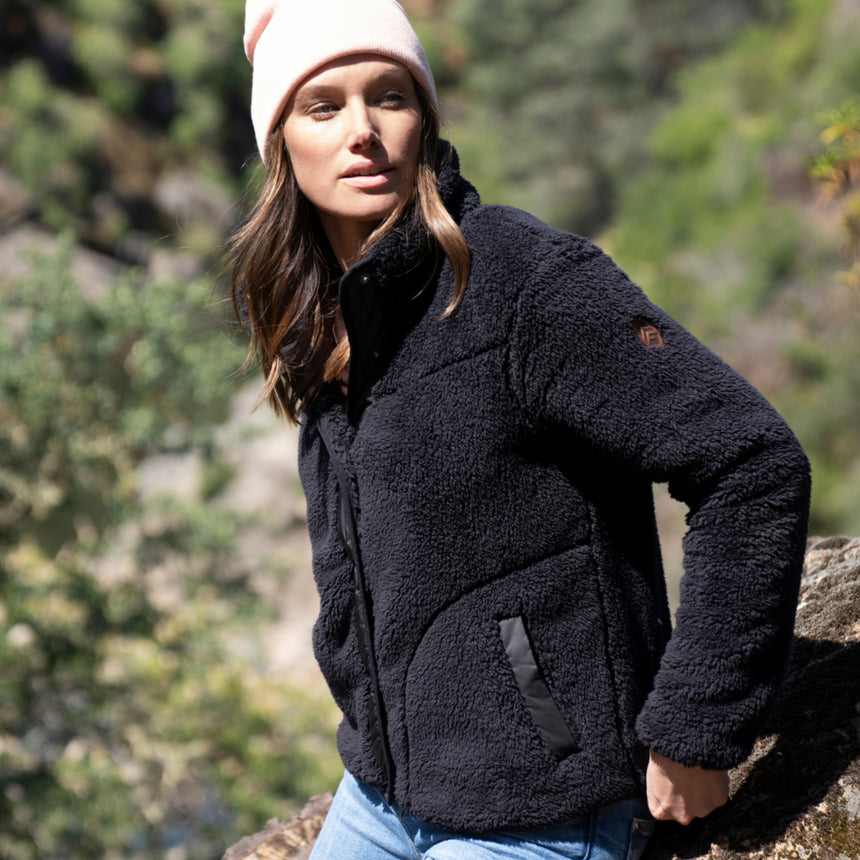 Woman wearing Free Country Women's Sherpa Butter Pile® Button Front Jacket in black  with a full front button opening, stand collar, lower pockets, and soft butter pile fabric. light grey background. Perfect women’s jacket for fall weather.