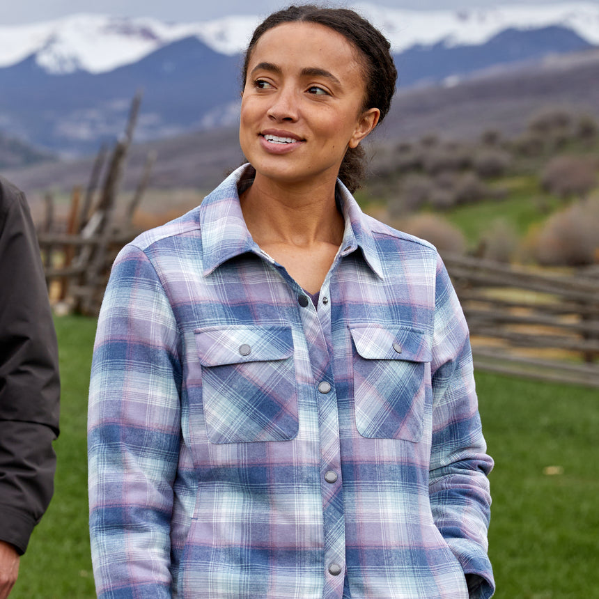 Woman wearing Free Country Women's Koshi Adirondack Flannel Shirt Jacket in pink and blue and white plaid with a full front button opening, soft lining, chest pockets, light grey background. Best women’s jacket for winter weather.