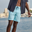Man wearing Free Country Men's Textured Surf Swim Short in Aqua, size M, made from moisture wicking stretch performance fabric featuring  a half back elastic waistband and fly front drawstring front closure #color_aqua