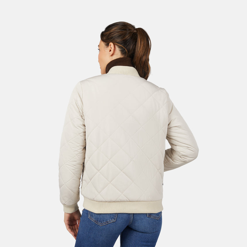 A woman with brown hair in a ponytail faces away from the camera, wearing the Clearance Women's Stratus Lite Reversible Quilted Bomber Jacket and blue jeans against a plain white background.