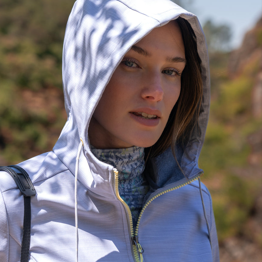 Woman wearing Free Country Women's Alps Super Softshell® Jacket in textured ligth grey with a full front zipper opening, soft lining, attached hood with adjustable drawcords, and water resistant and wind resistant stretch performance fabric. Perfect women’s  jacket for fall weather.