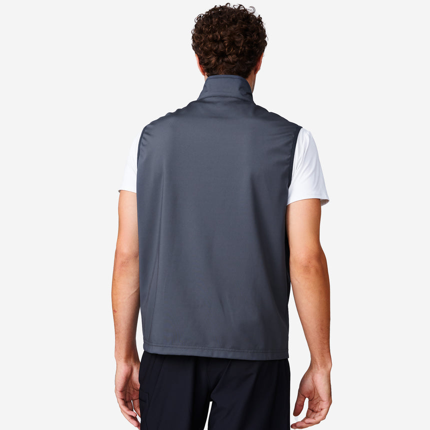 A man with curly hair, seen from behind, wears the Clearance Men's High Stretch Full Zip Vest in slate gray over a white short-sleeve shirt and black pants, set against a plain white background.