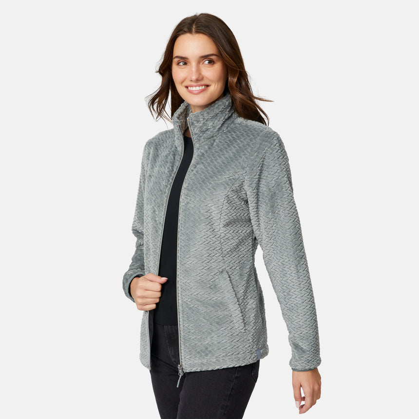 A smiling woman wears a grey Women’s Cable Braided Butter Pile® Jacket, featuring a soft, textured cable braided pattern and a high collar.