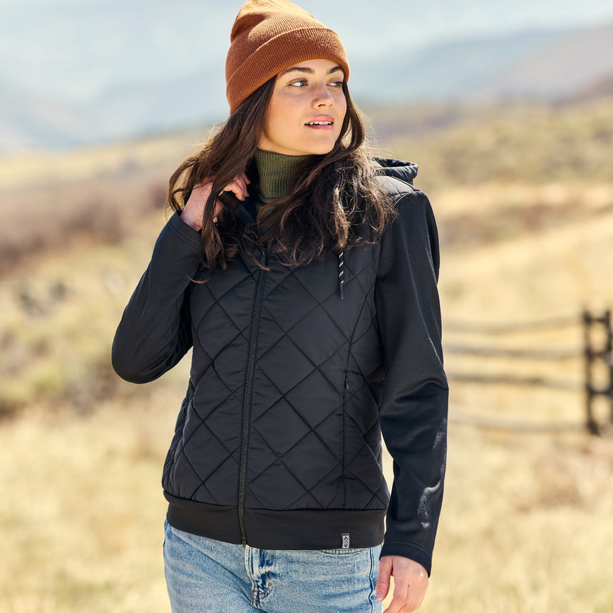 Woman wearing a black quilted jacket and brown beanie in an outdoor setting
