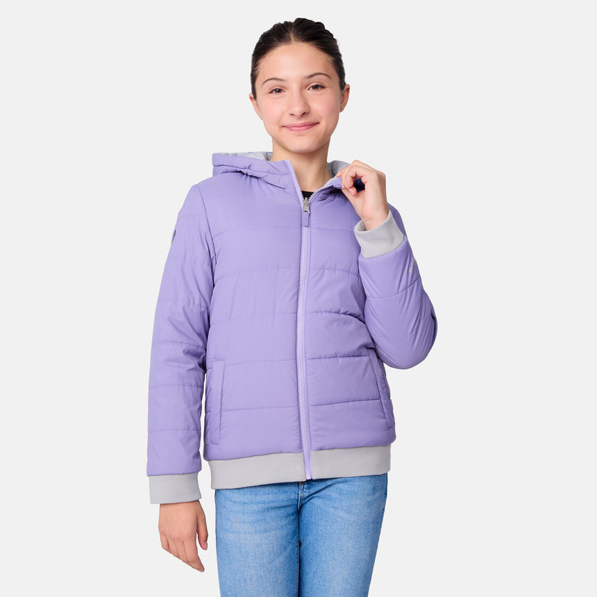 A young person wearing the Girls' Poofie Reversible Puffer Jacket by Clearance in light purple, featuring gray cuffs and a water-resistant finish, stands against a plain white background, smiling and holding the zipper.
