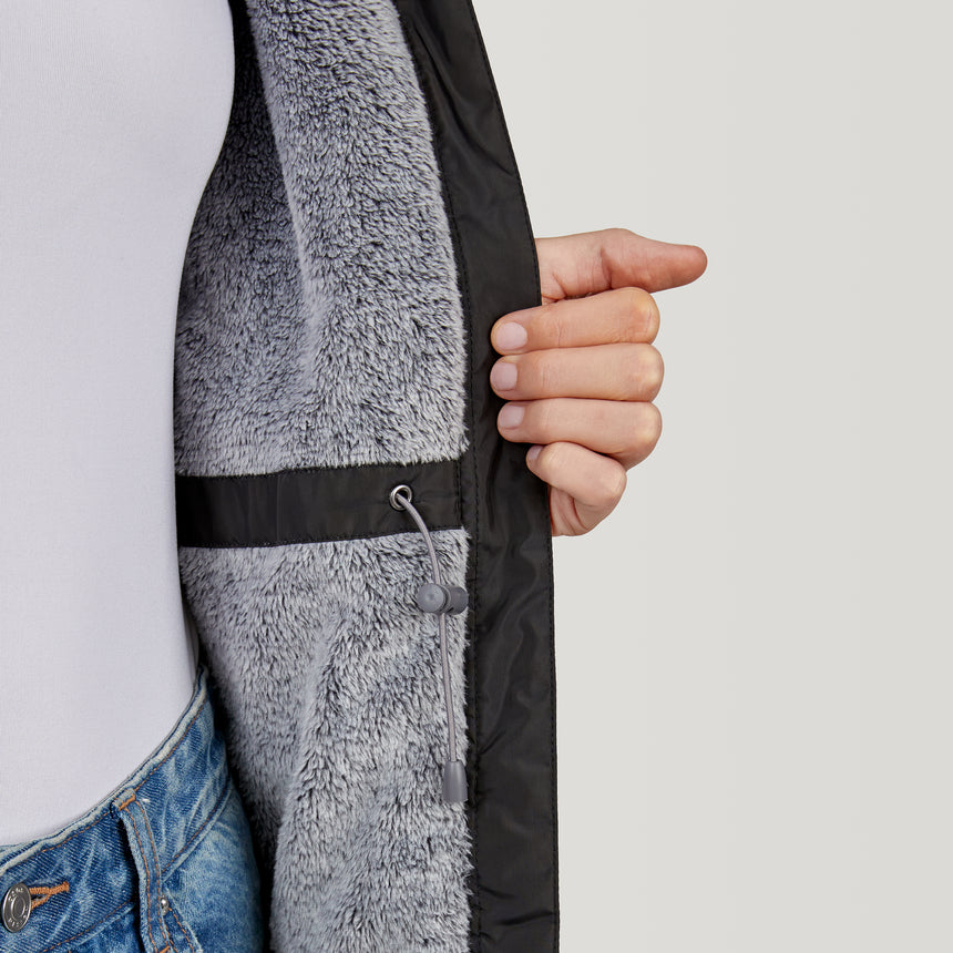 Woman wearing Free Country Women's Cascade Windshear Jacket in black with a full front zipper opening, soft lining, and water resistant and wind resistant recycled polyester stretch performance fabric, light grey background. Best women’s jacket for windy weather.