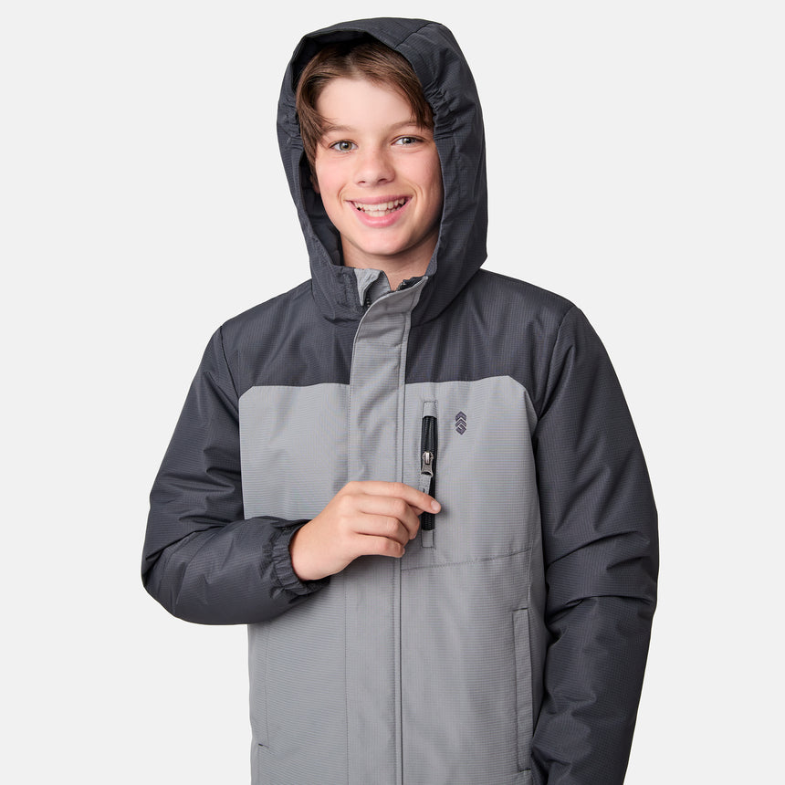 A smiling boy wearing the Clearance Boys' Mount Avon Midweight Jacket in two-tone gray unzips the chest pocket while standing against a plain white background.