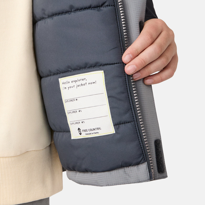 A hand holds open a Clearance Boys' Mount Avon Midweight Jacket, revealing an interior label that reads, "Hello explorer, in your jacket now!" This water-resistant kids' jacket features spaces labeled Explorer #1, #2, and #3 alongside the Clearance brand logo.