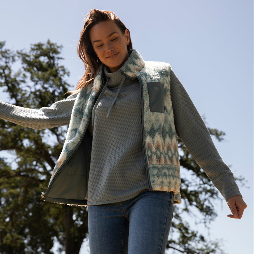 Woman wearing the Free Country Women's Venture Stratus Lite Reversible Vest in light blue, featuring a geometric-print Butter Pile® lining and horizontal quilted overlay