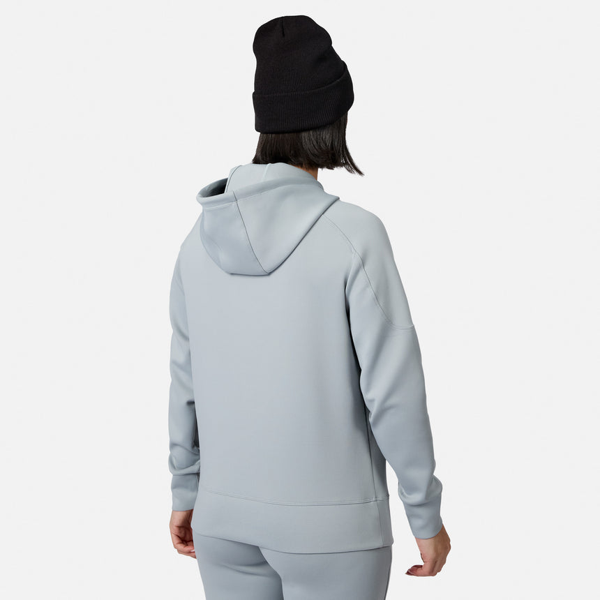 A person in a light gray Women’s Sueded Lush Pullover Hoodie by Free Country and matching pants, wearing a black beanie, stands facing away from the camera against a plain white background.