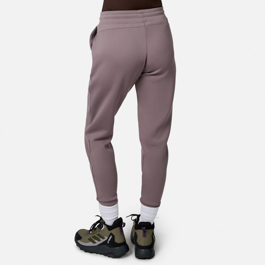 Model wearing Free Country Women’s Sueded Lush Jogger in mauve with white socks and green-black sneakers, shown from the back against a plain white background.