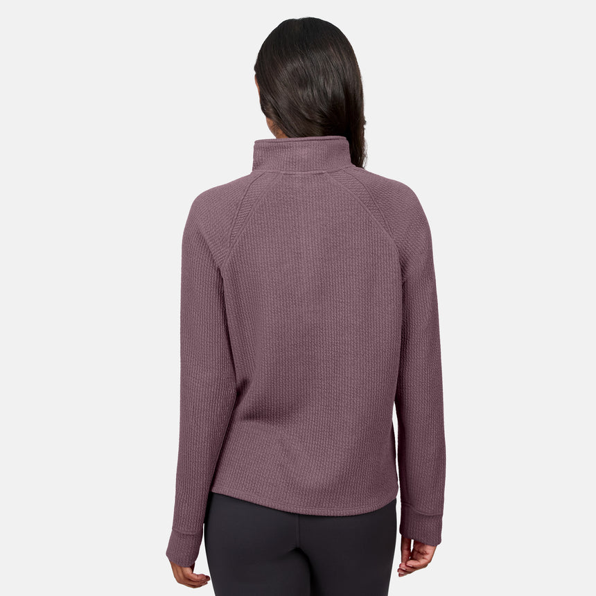 A person faces away, wearing the Free Country Women’s Ripple Knit Half Zip Top in mauve with gray pants against a plain white background—ideal for casual layering.