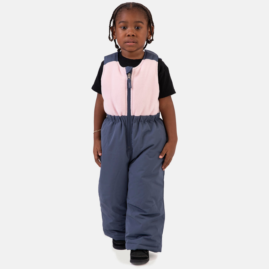Young girl wearing the Free Country Girls' Toddler Boarder Jacket and Bib Pant Set, featuring a light pink and navy hooded jacket with Butter Pile® lining and matching navy snow pants, designed for winter play.