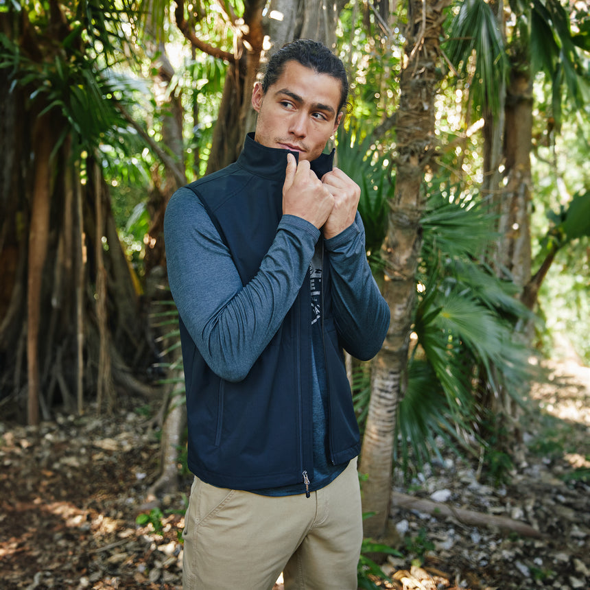 Man wearing Free Country Men's Stretch Rip Stop Adventure Vest in Dark Black, size M, made from wind resistant lightweight stretch polyester performance fabric featuring a convertible collar and full front zip closure #color_black