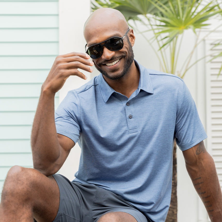 Man wearing Free Country Men's SunFree UPF Polo Shirt in Wave, size M, made from anti-odor, breathable lightweight recycled polyester performance fabric featuring a classic active fit