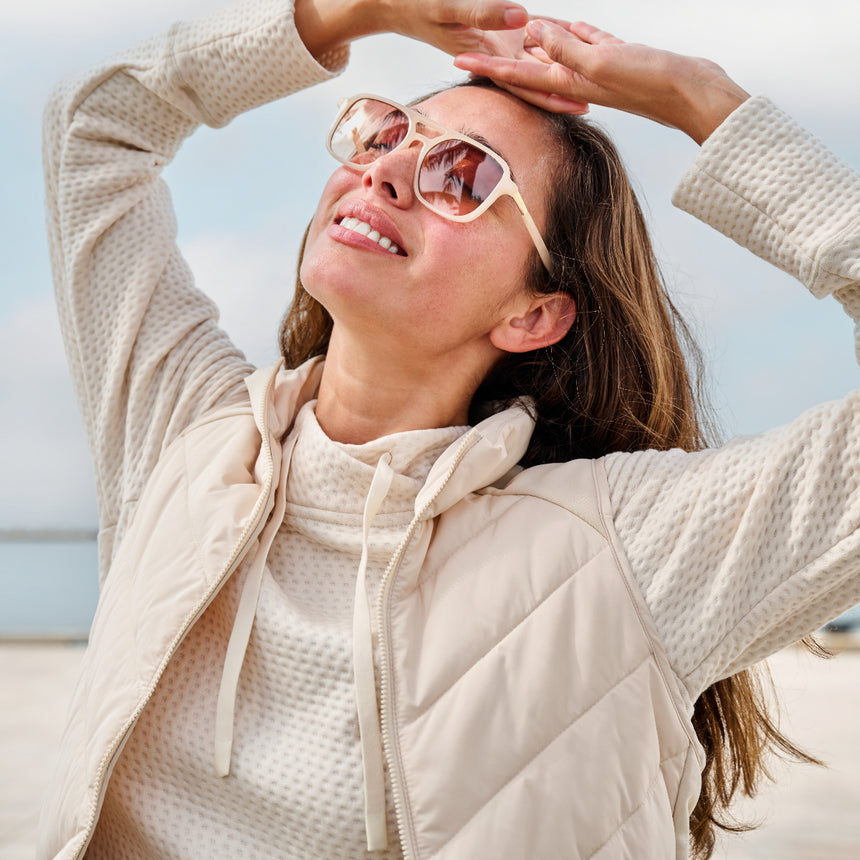Woman wearing the Free Country Women's Quilted Hybrid Vest in white, featuring a unique quilted design with stretch knit panels and REPREVE® synthetic fill.