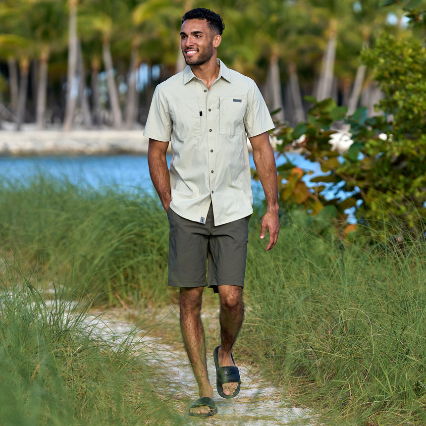 Man wearing Free Country Men's Nylon Stretch Casual Short in Olive, size M, made from lightweight stretch performance fabric featuring a water repellent finish, slanted side pockets, and side leg zippered coin pocket #color_olive