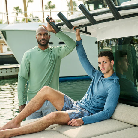 Two men in colorful Free Country men's swim board shorts run on the beach.