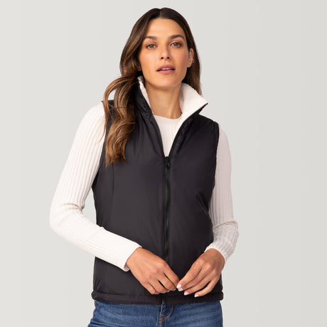 A woman with long brown hair models the Women's Cascade Canvas 3-in-1 Systems Jacket by Clearance over a white ribbed sweater and blue jeans, standing against a plain light gray background.