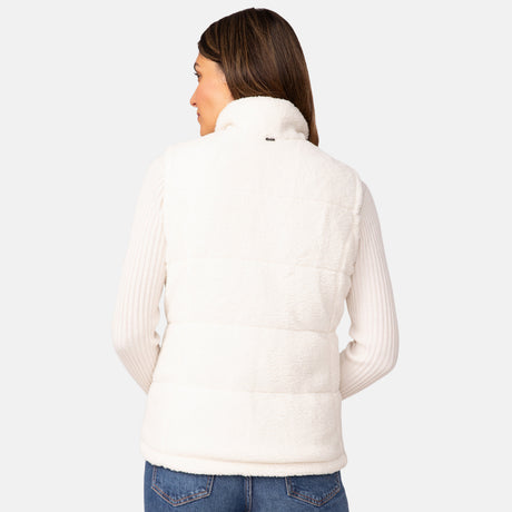 A woman with brown hair, seen from behind, wears the Clearance Women's Cascade Canvas 3-in-1 Systems Jacket over a ribbed white sweater and blue jeans against a plain light background.
