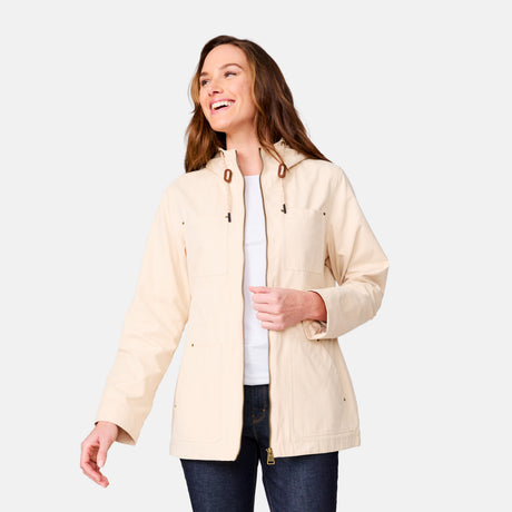 A woman smiles and looks to her left against a plain light gray background, wearing the Clearance Women's Lightweight Cascade Canvas Jacket over a white shirt and dark jeans.