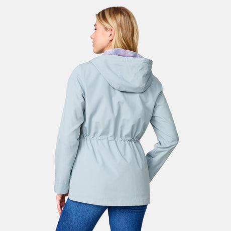 A woman with blonde hair models the Women's Lightweight Cascade Canvas Jacket by Clearance in light blue, paired with blue jeans, as she looks over her left shoulder against a plain white background.