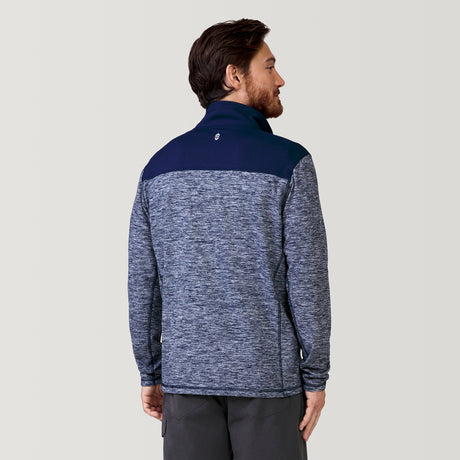 A man with brown hair and a beard stands with his back to the camera, wearing the Clearance Men's Sueded Spacedye 1/2 Zip Colorblock Mock Neck Shirt in blue and gray pants against a plain light gray background.