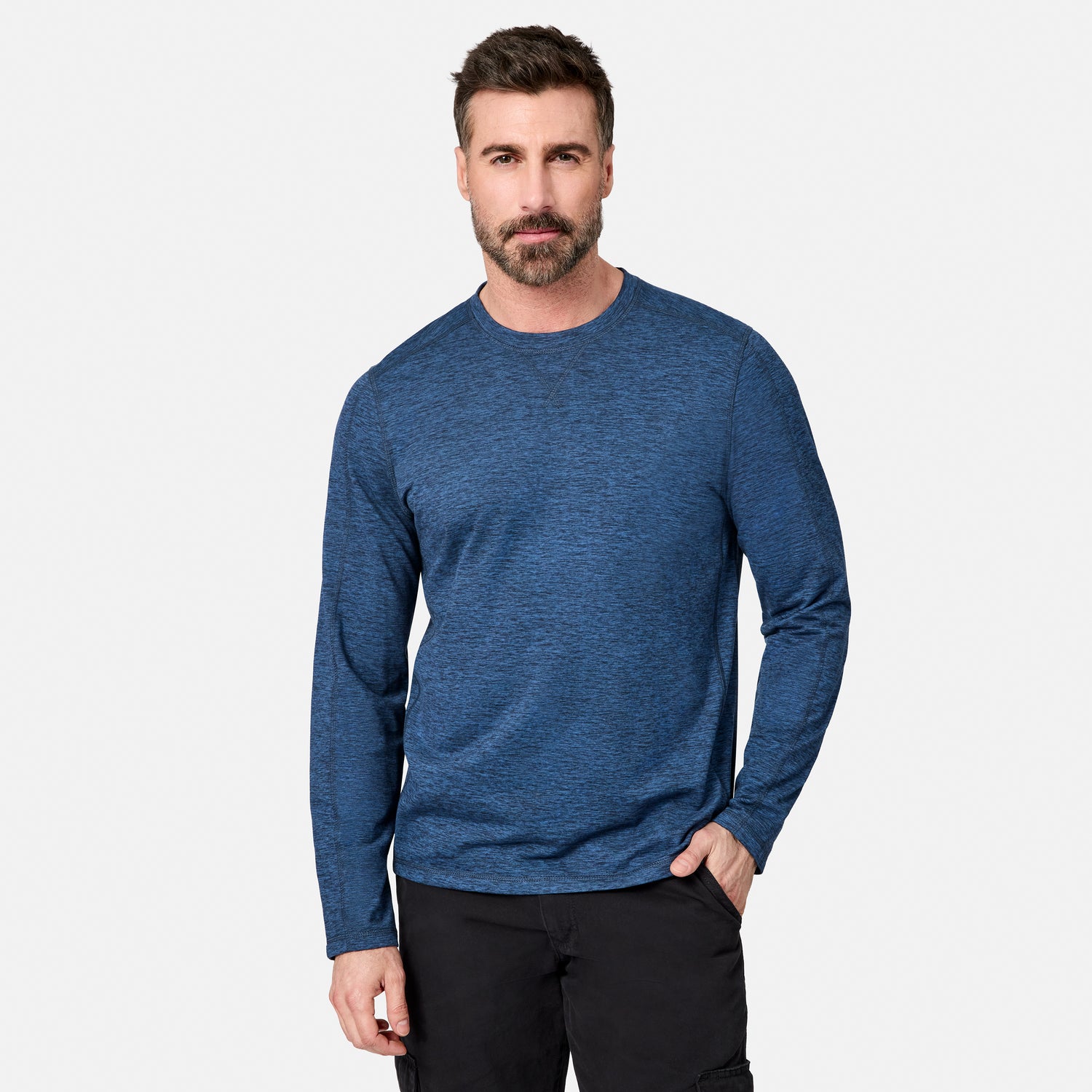 [Model is wearing size M.] A man wearing a heathered blue long-sleeve crewneck shirt and black pants, standing against a light gray studio background.
