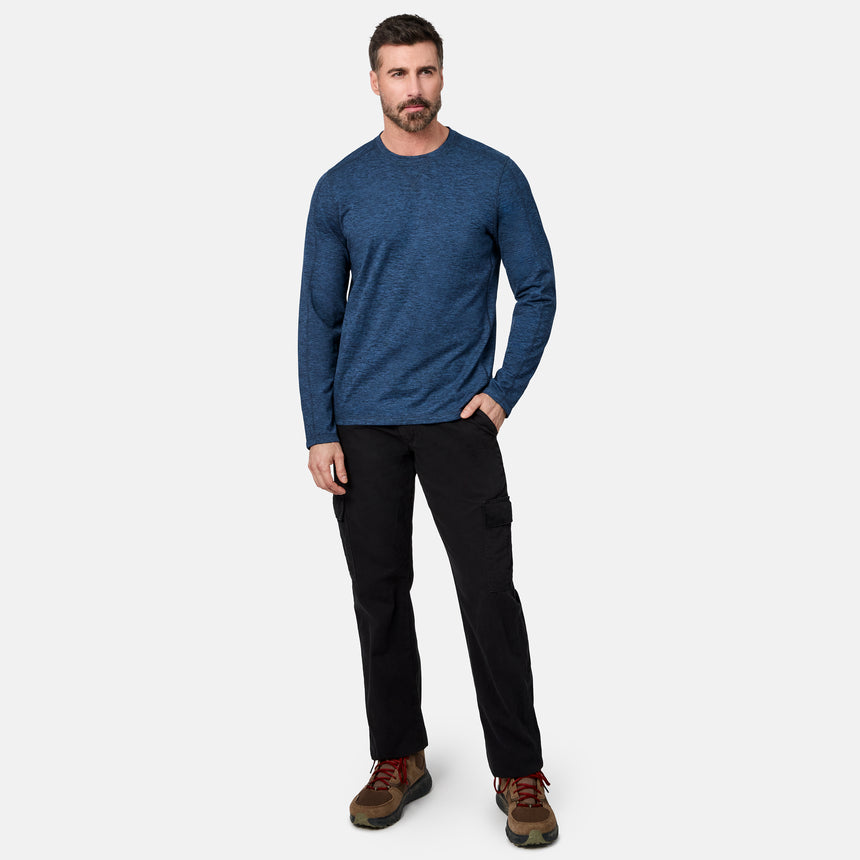 [Model is wearing size M.] A man wearing a blue long-sleeve crewneck shirt, black cargo pants, and brown hiking boots, standing against a light gray studio background.