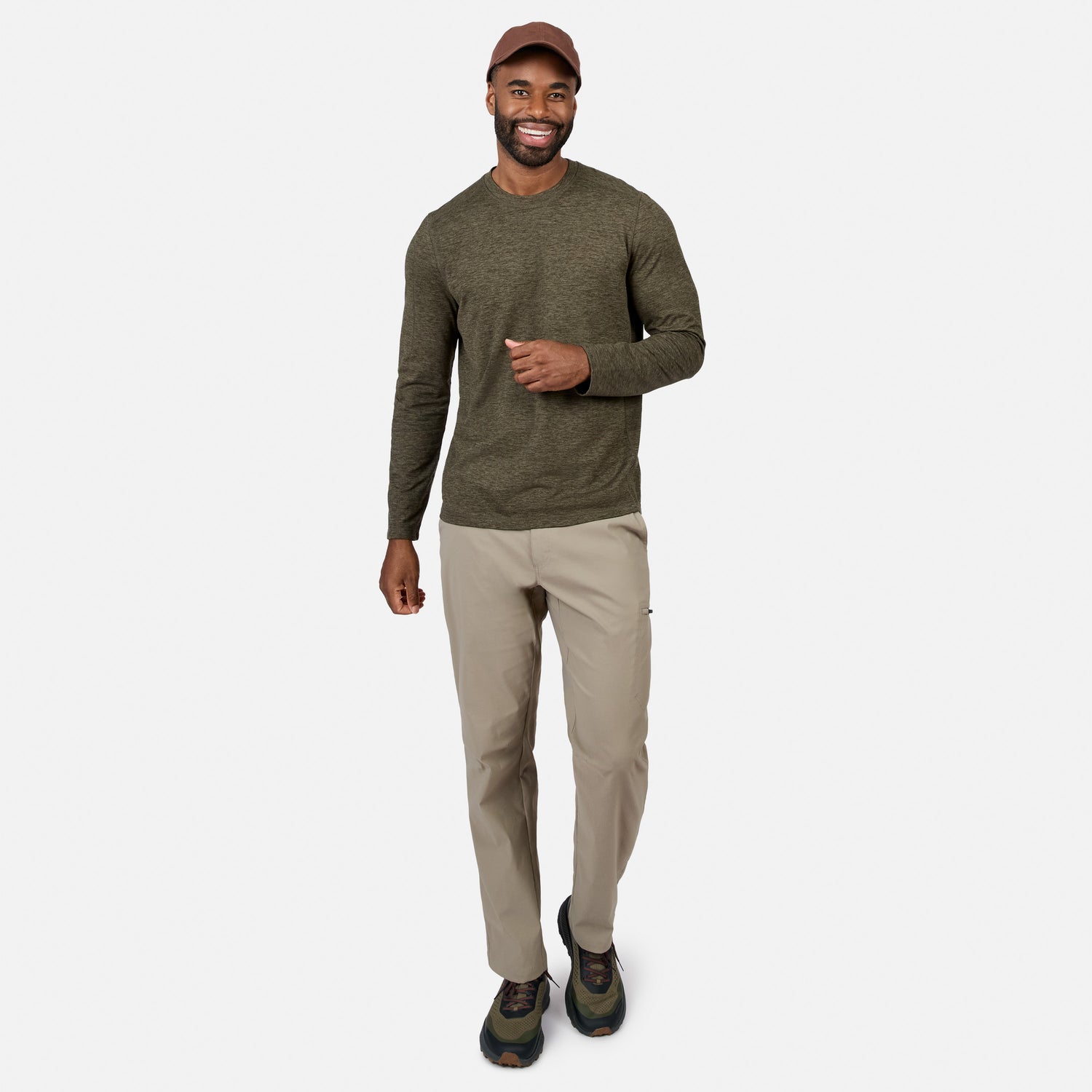 [Model is wearing size M.] A man modeling a dark olive green long-sleeve crewneck shirt, beige hiking pants, and hiking boots against a light gray studio background.