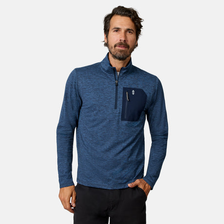 [Model is wearing size M.] A man wearing a heathered blue long-sleeve quarter-zip pullover with a dark navy chest pocket, paired with black pants, against a light gray studio background.