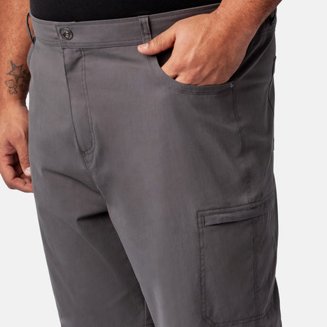 A person wears gray Men's Stretch Active Poplin Trek Cargo Shorts by Clearance with their right hand in the front pocket, showing the waist and upper leg. The shorts have a side pocket, and a tattoo is visible on their left arm.